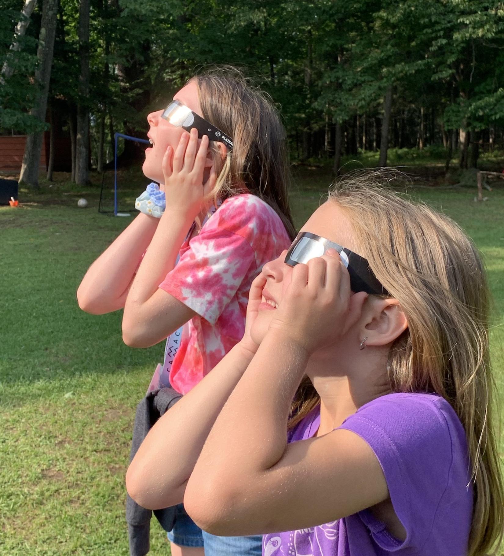 Kids looking at the Sun with eclipse glasses