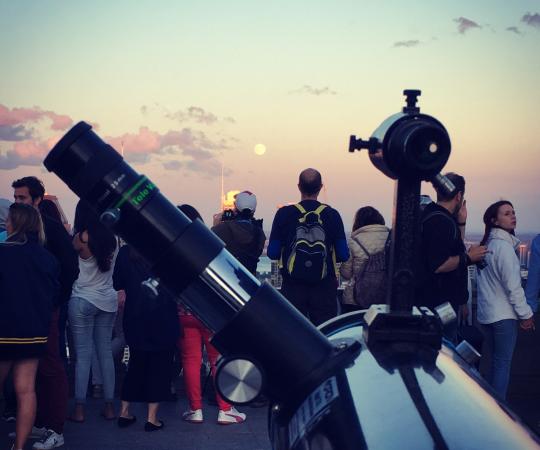 Des gens surplombant Montréal alors que la pleine lune se lève à l'horizon