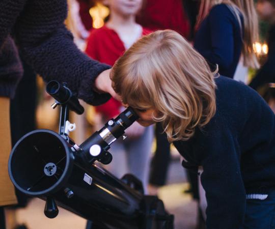Child looking through telescope during private event